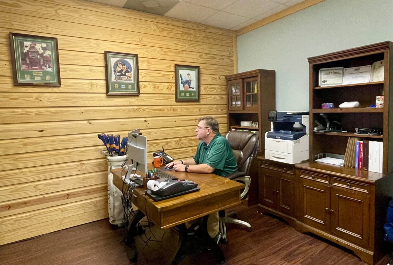 A man sitting at his desk in front of a laptop.